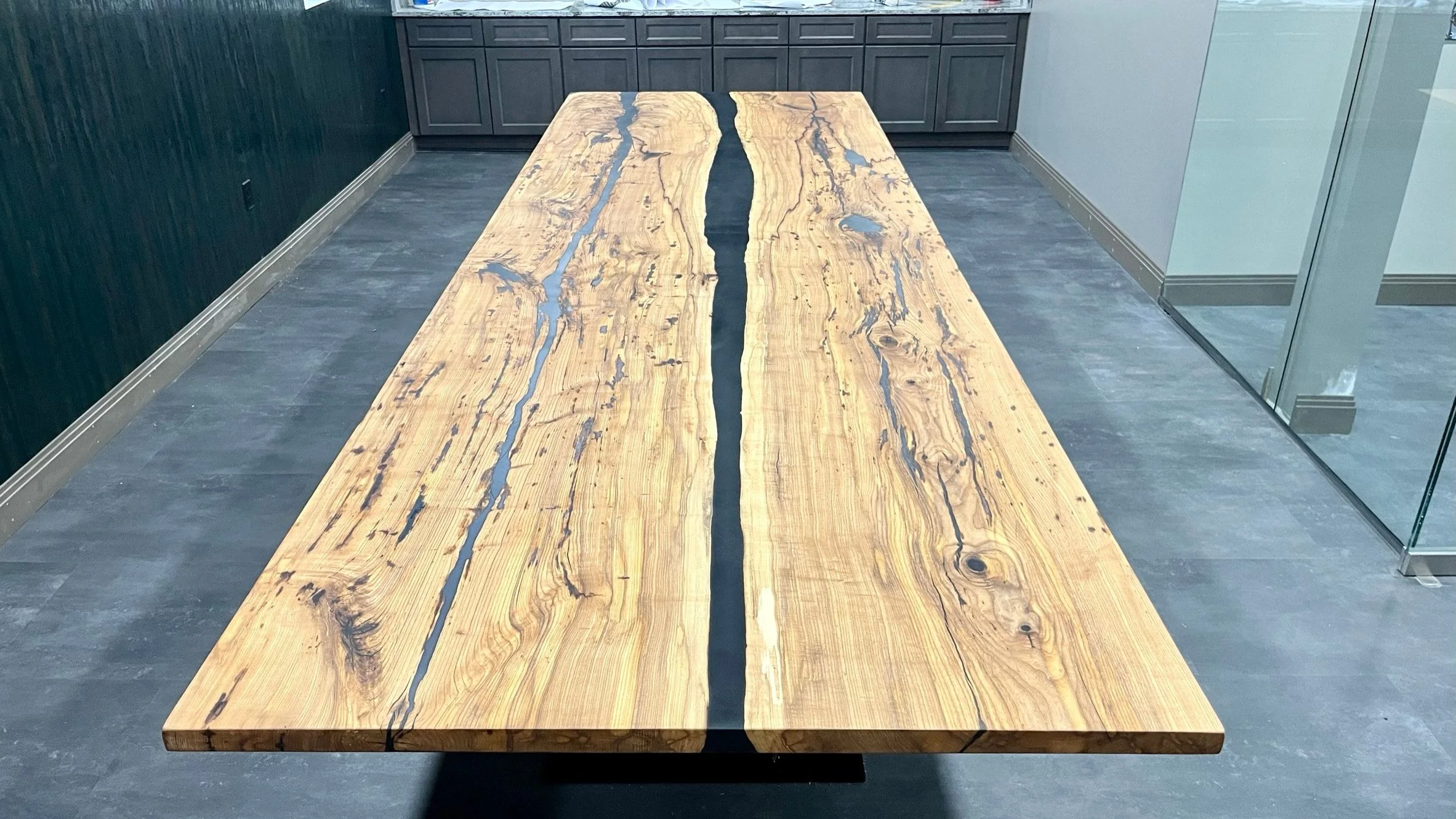 The full length of the conference table top from above, two figured boards either side of a dark channel.