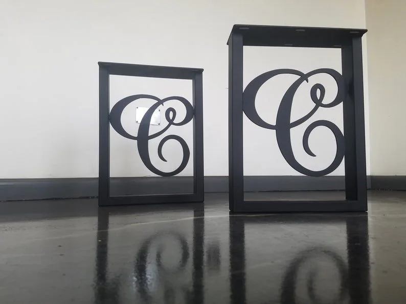 Two black metal frames with ornate letter