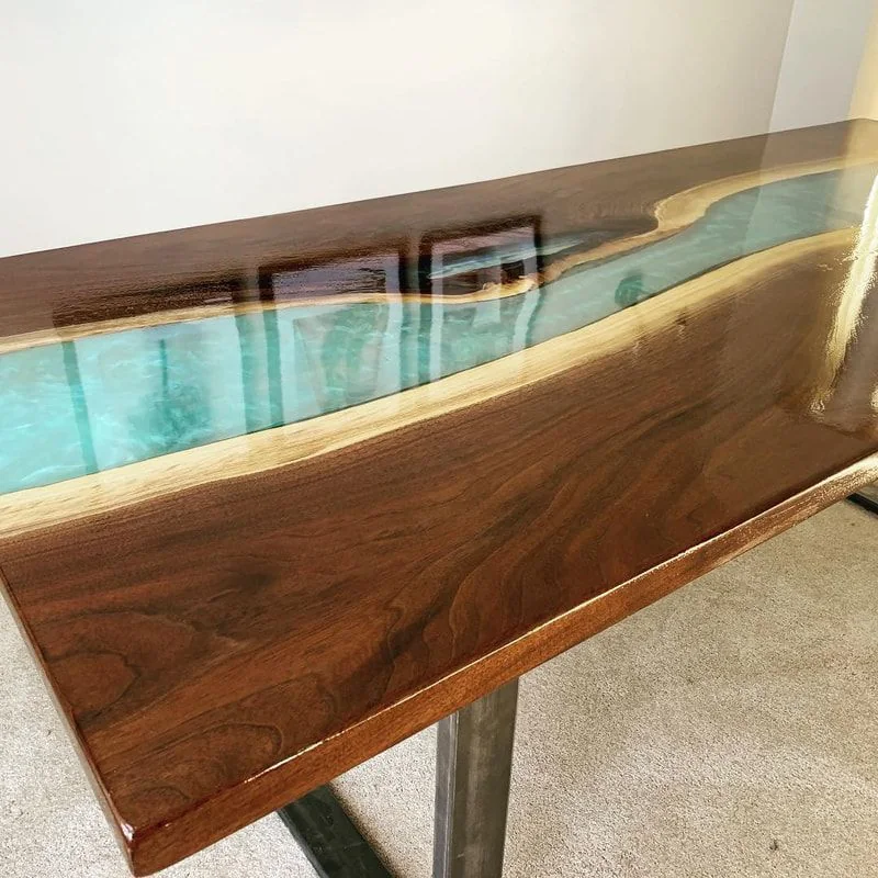 Wood table with glossy finish and vibrant blue resin river through center.