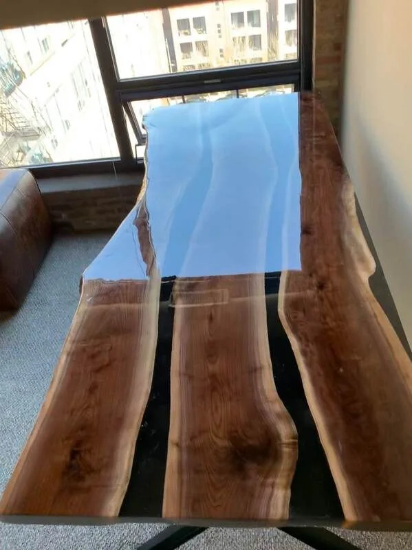 Irregular-shaped wood and clear resin table with polished finish in sunlit room.