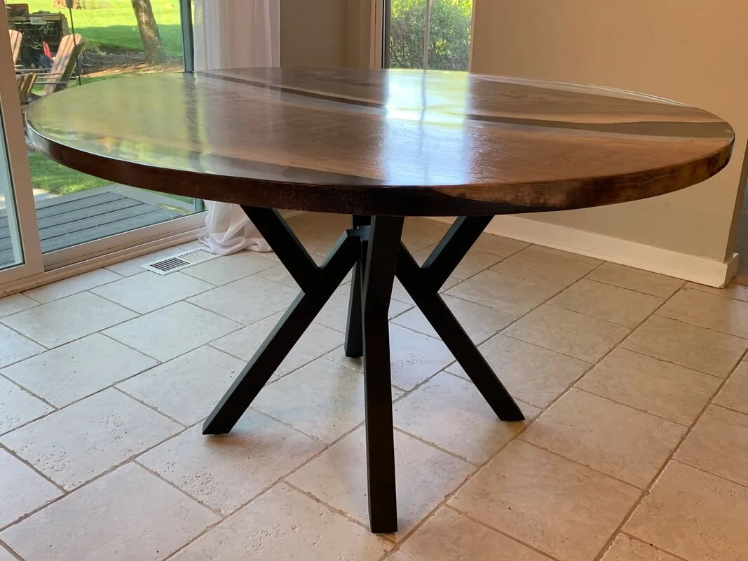 Round Epoxy River table with metal base, photographed against a dark studio wall.