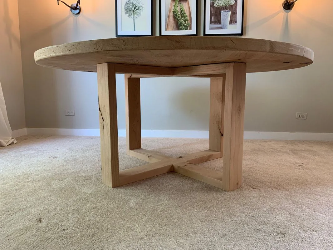 Round wood table with thick top and Open Looped base, photographed against a dark studio wall.