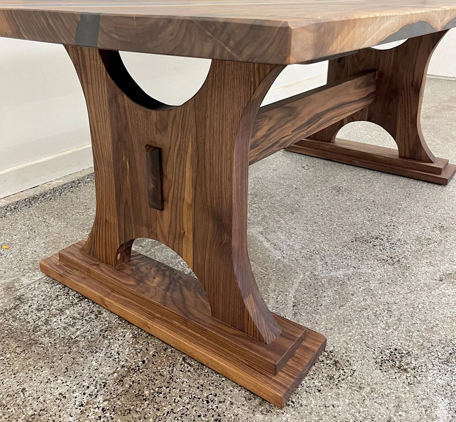 A walnut trestle base with arched cut-outs, a heavy stretcher and stepped feet.