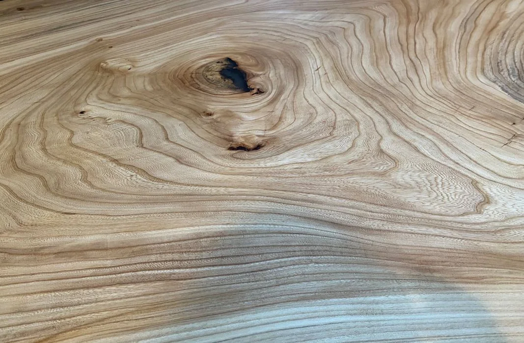 Close-up of natural wood surface with prominent grain patterns and knots, highlighting organic texture and craftsmanship.