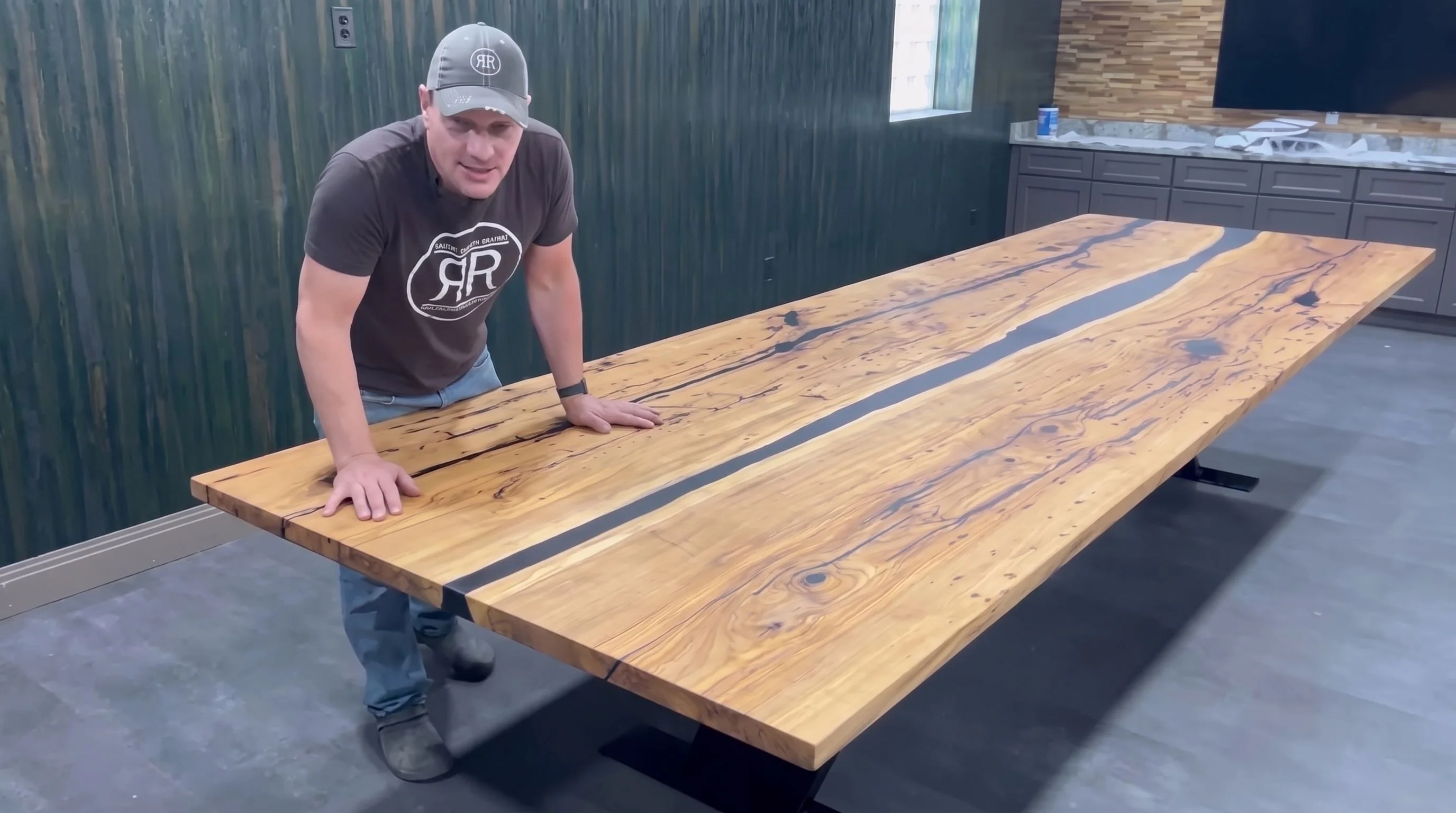 Rob Showalter leaning on a long river table with a black steel base.